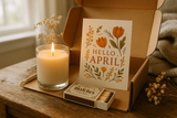 a subscription box with a candle, postcard (theme of the month), and matchbox preferably in use or placed in a more natural lit setting for background